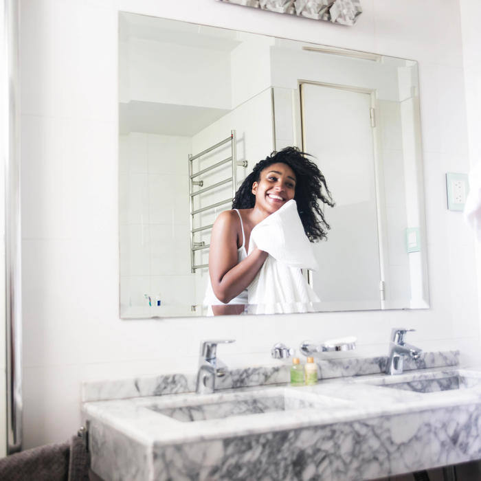 Woman looking in mirror while she dries her hair