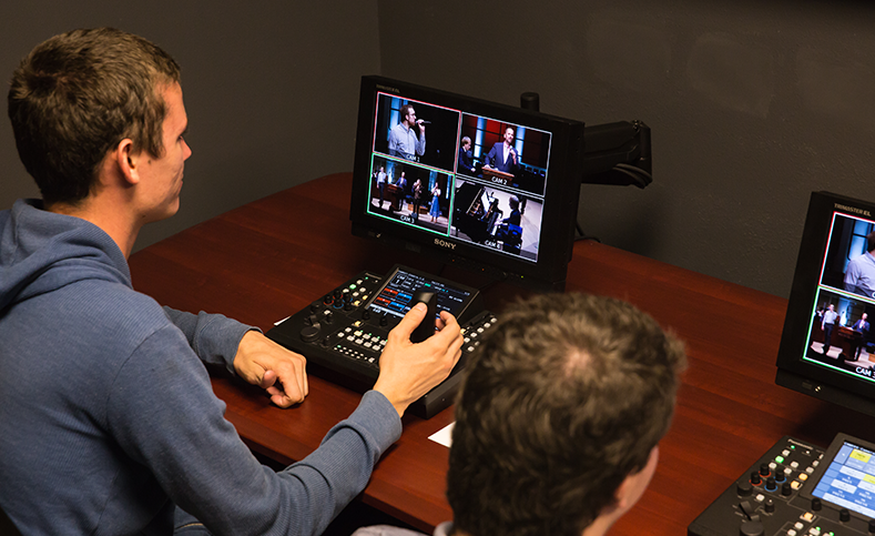 HOMME exploitant un contrôleur vidéo de diffusion professionnelle avec plusieurs écrans affichant des flux en direct.