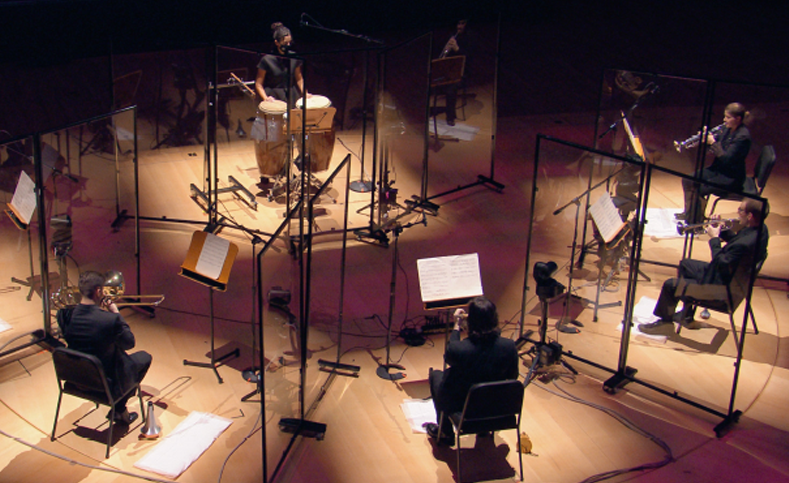 Musiciens d'orchestre se produisant sur scène avec des barrières sonores et des microphones.