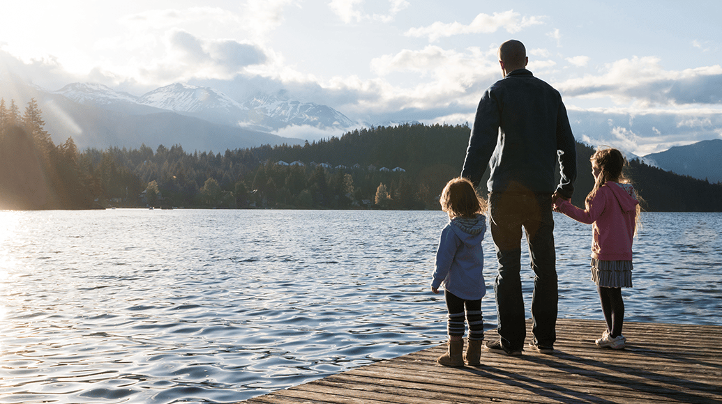 Father standing with children at the side of a lake