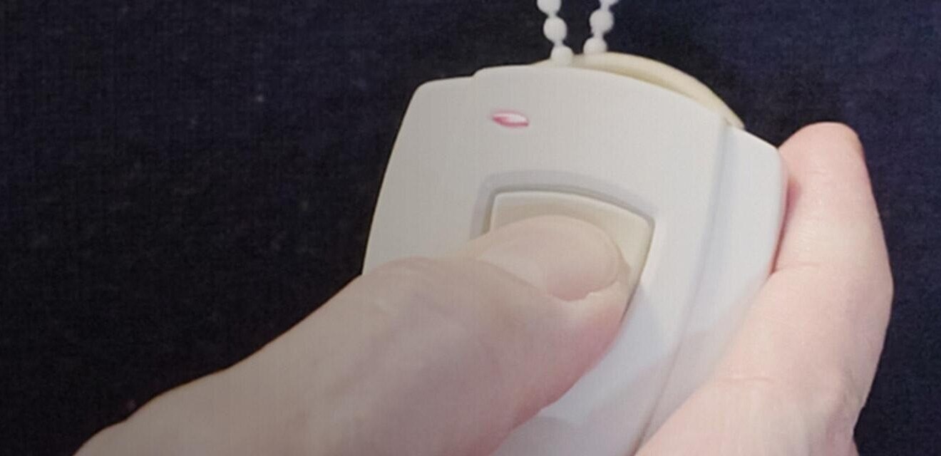 Closeup of person pressing emergency button on pendant