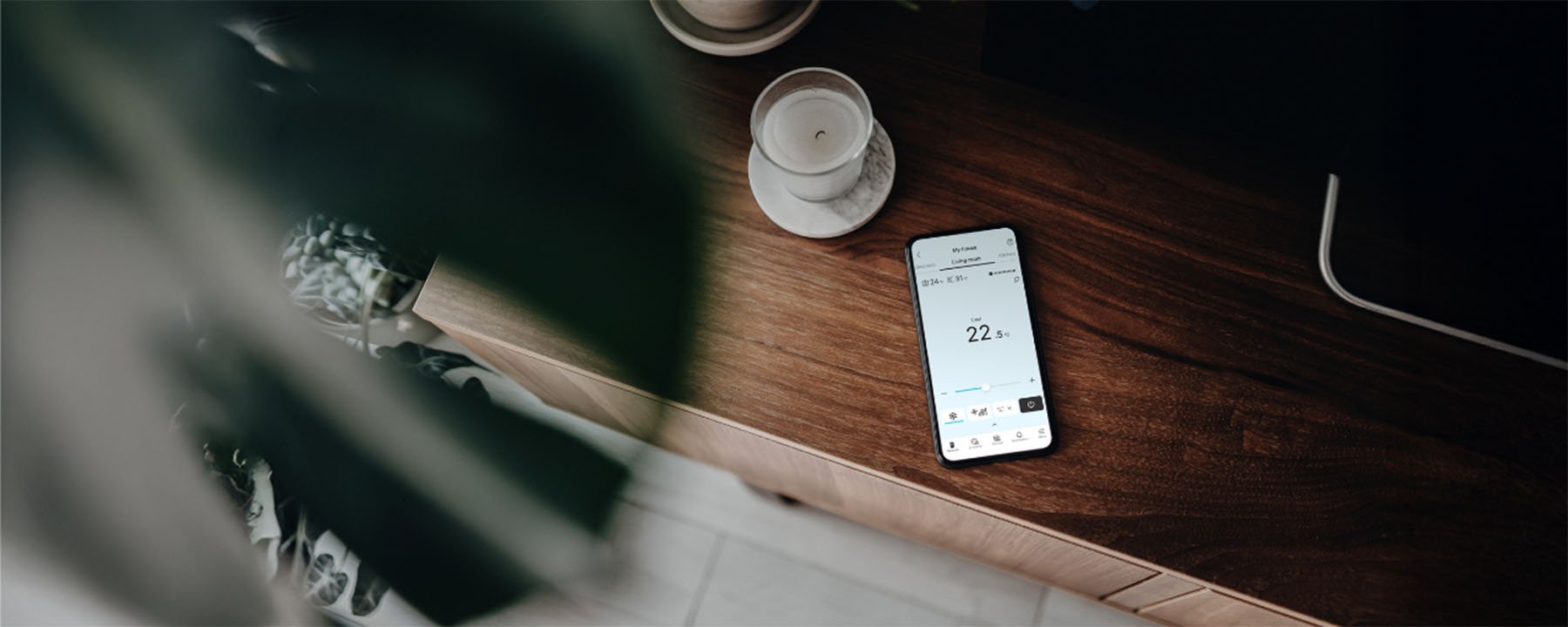 Application Comfort Cloud en arrière-plan sur un téléphone intelligent qui est situé sur un bureau près d'une chandelle