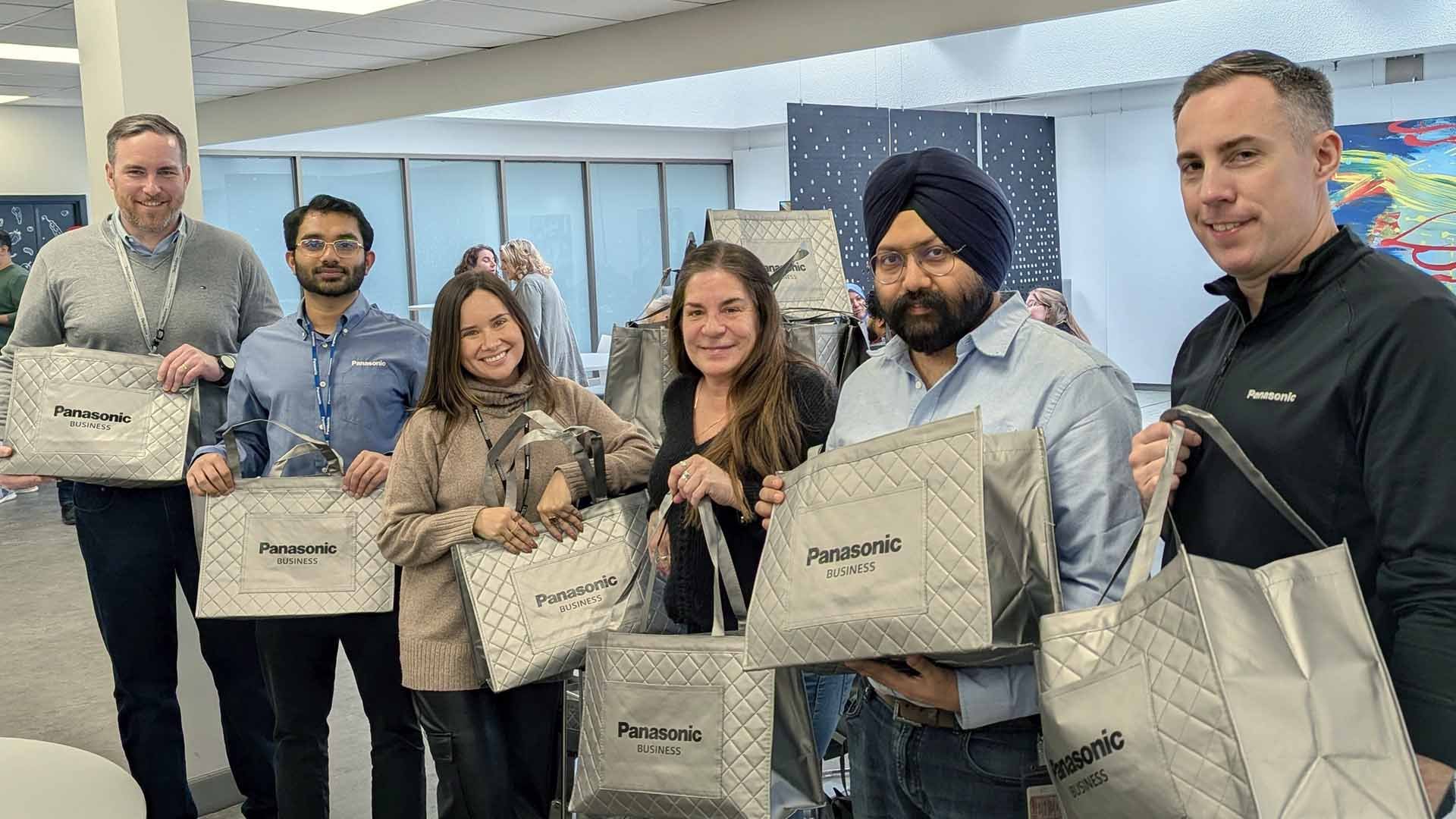 Groupe of people holding grey bags with Panasonic logo.