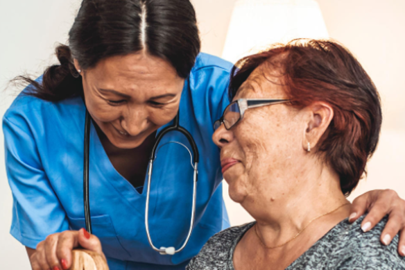 Nurse assisting elderly woman, both smiling, in a clinical setting.