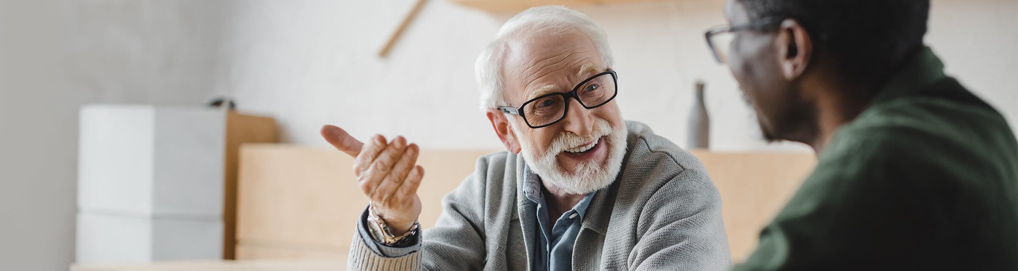 A senior is engaged in friendly conversation around a table