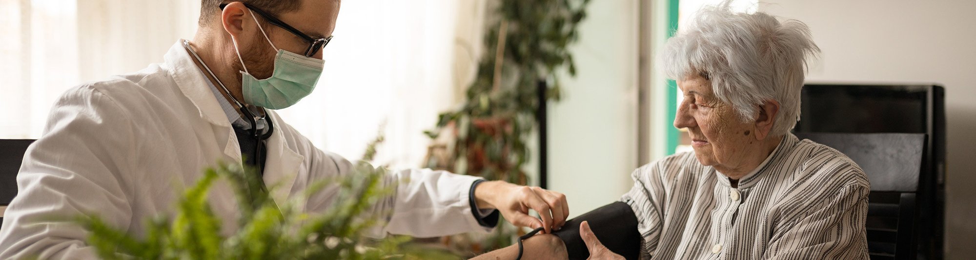 A doctor takes a senior's blood pressure