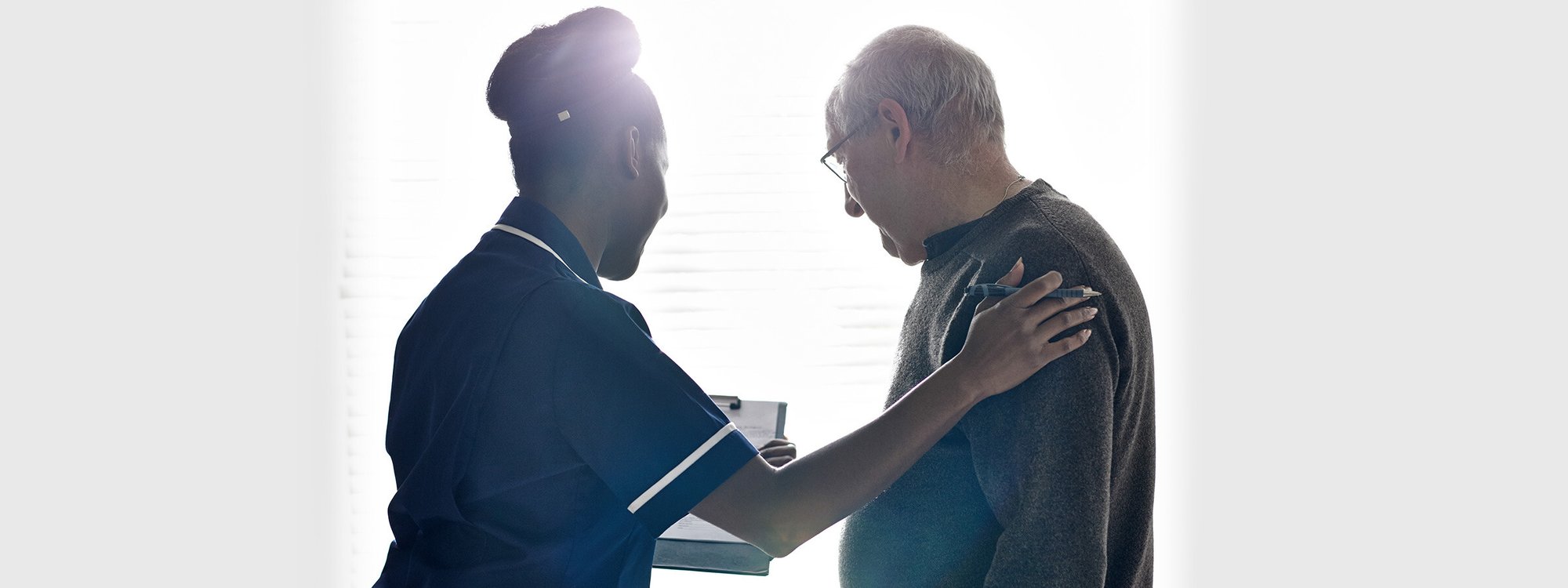 A senior and a nurse look at a clipboard
