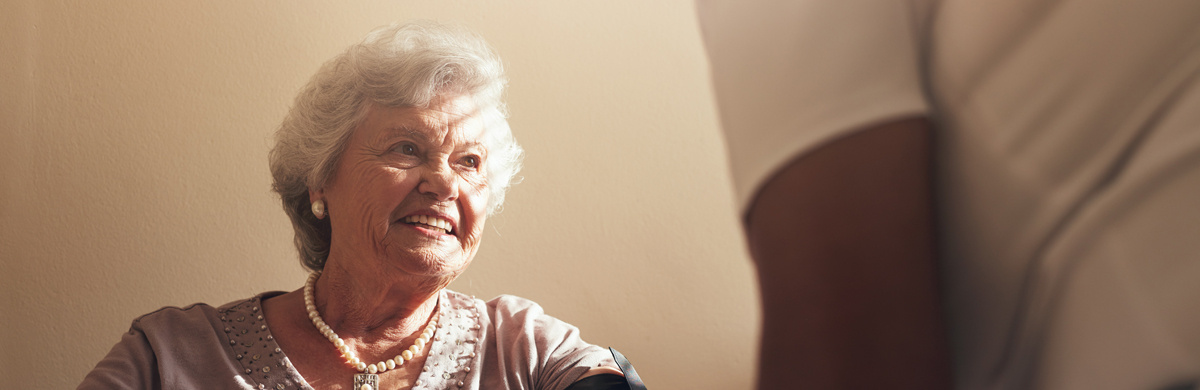 A smiling senior has her blood pressure taken