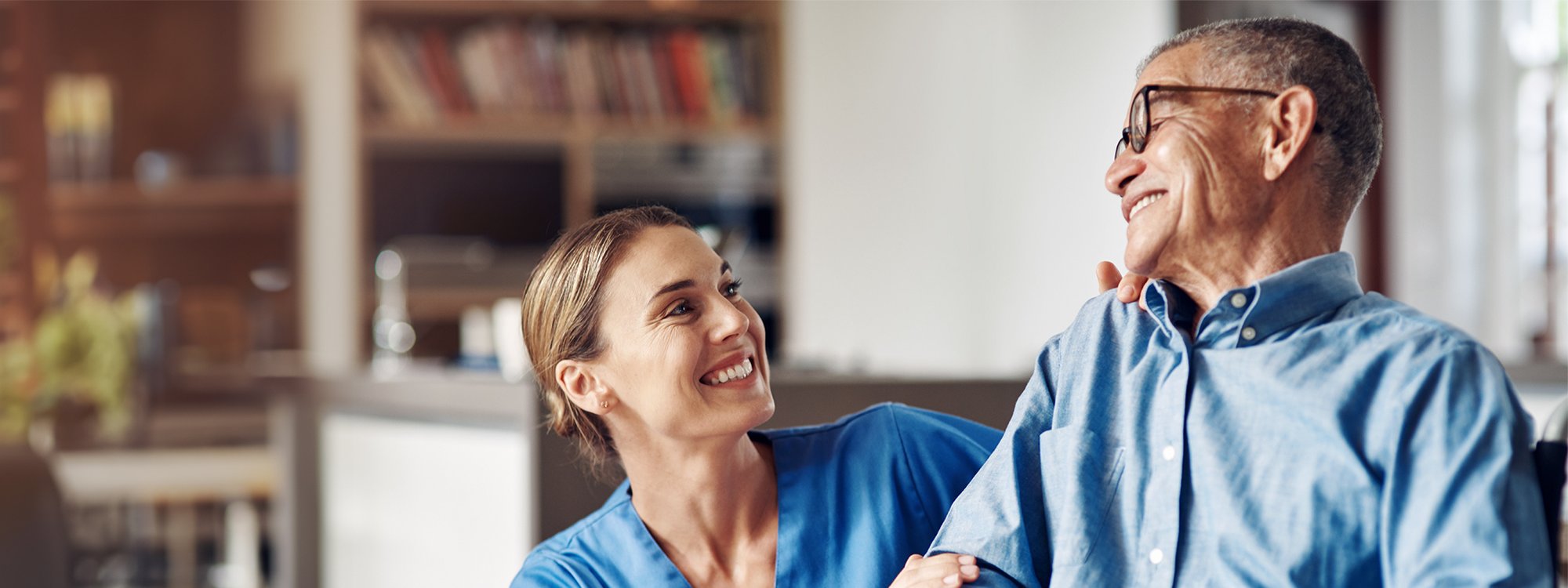 A nurse and a senior smile at each other