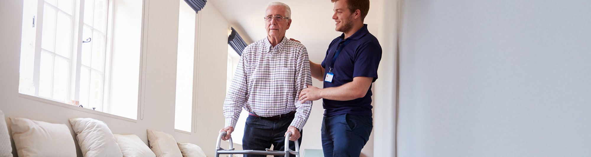 A senior with a walker is assisted by a support worker