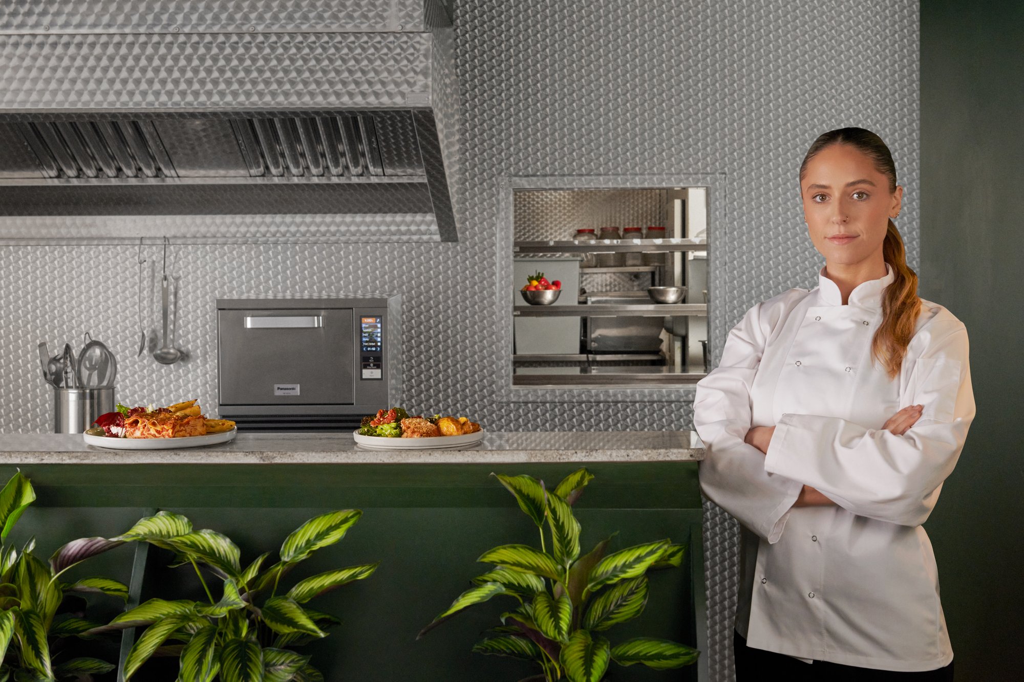 A chef standing next to Panasonic NE-SCV3N high speed oven in a professional commercial kitchen.
