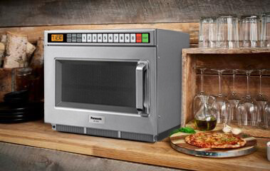 Panasonic commercial microwave sitting on countertop next to glassware