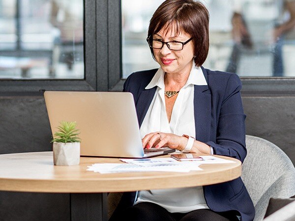 Professional woman sitting at round table working on laptop