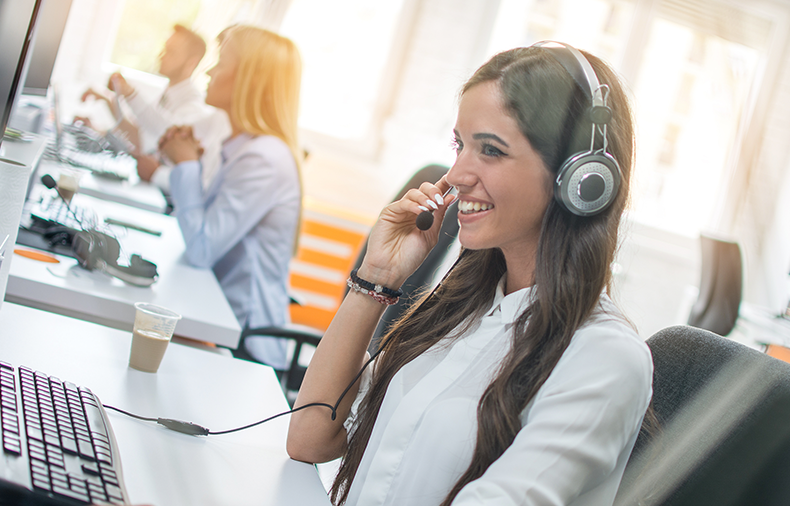 Woman working in office sitting at desk wearing a headset while assisting on a support call