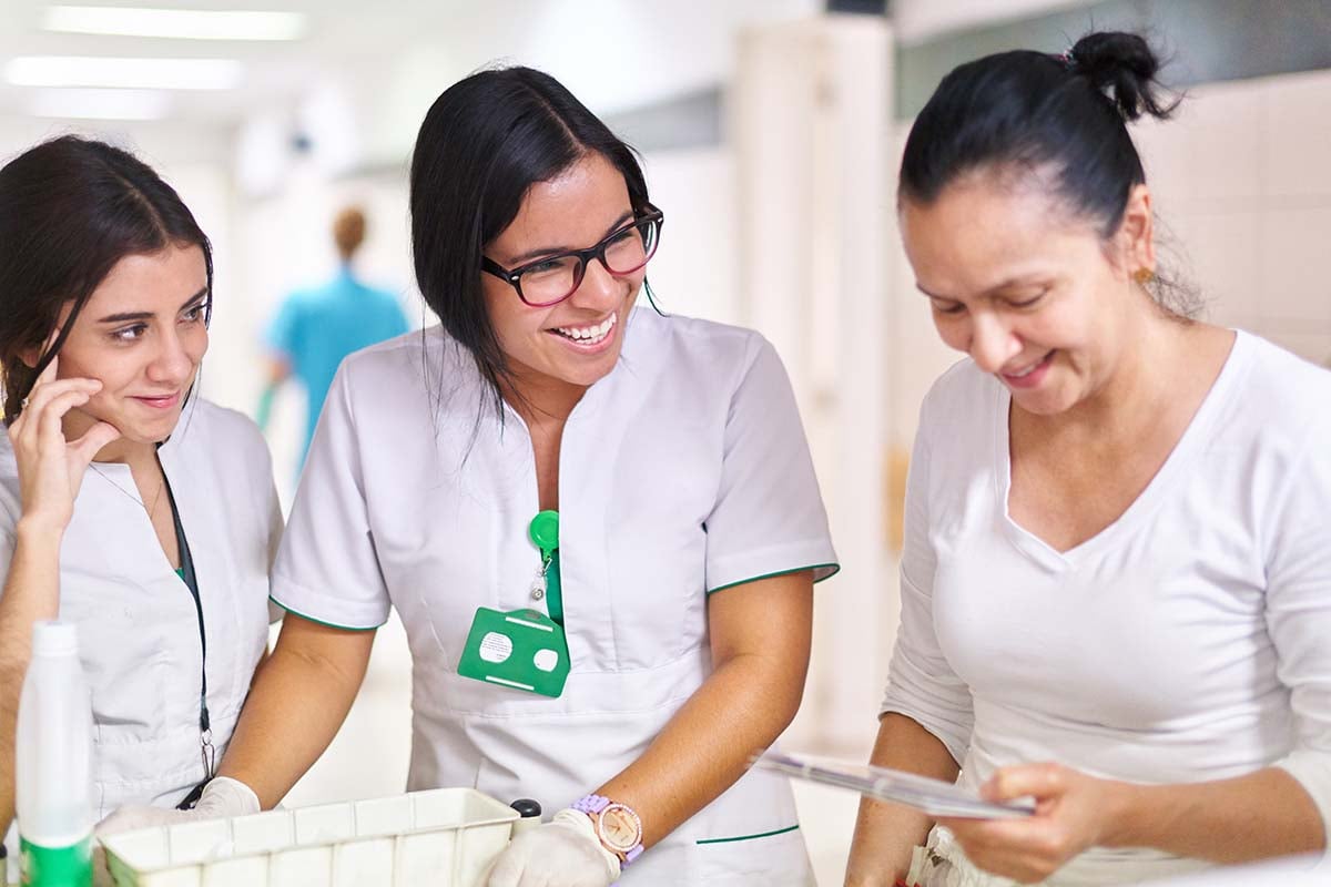 Three nurses smile as they work