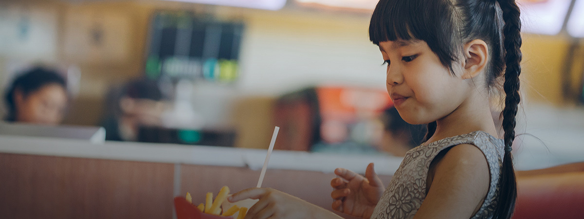 A young girl eats french fries in a McDonalds