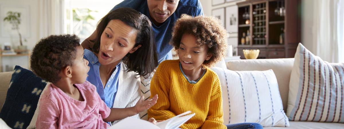 A family gathers around a book