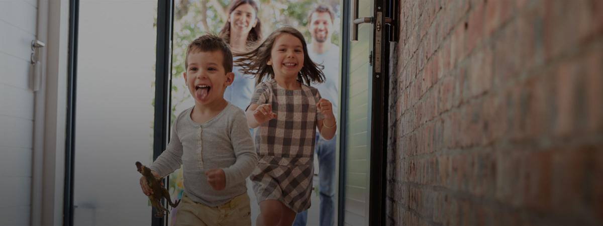 Excited children run through their front door with parents standing behind