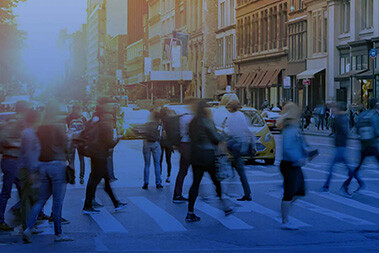 People walking quickly across street at crosswalk in city