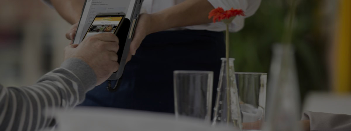 A restaurant customer taps their phone to a payment console help by a server