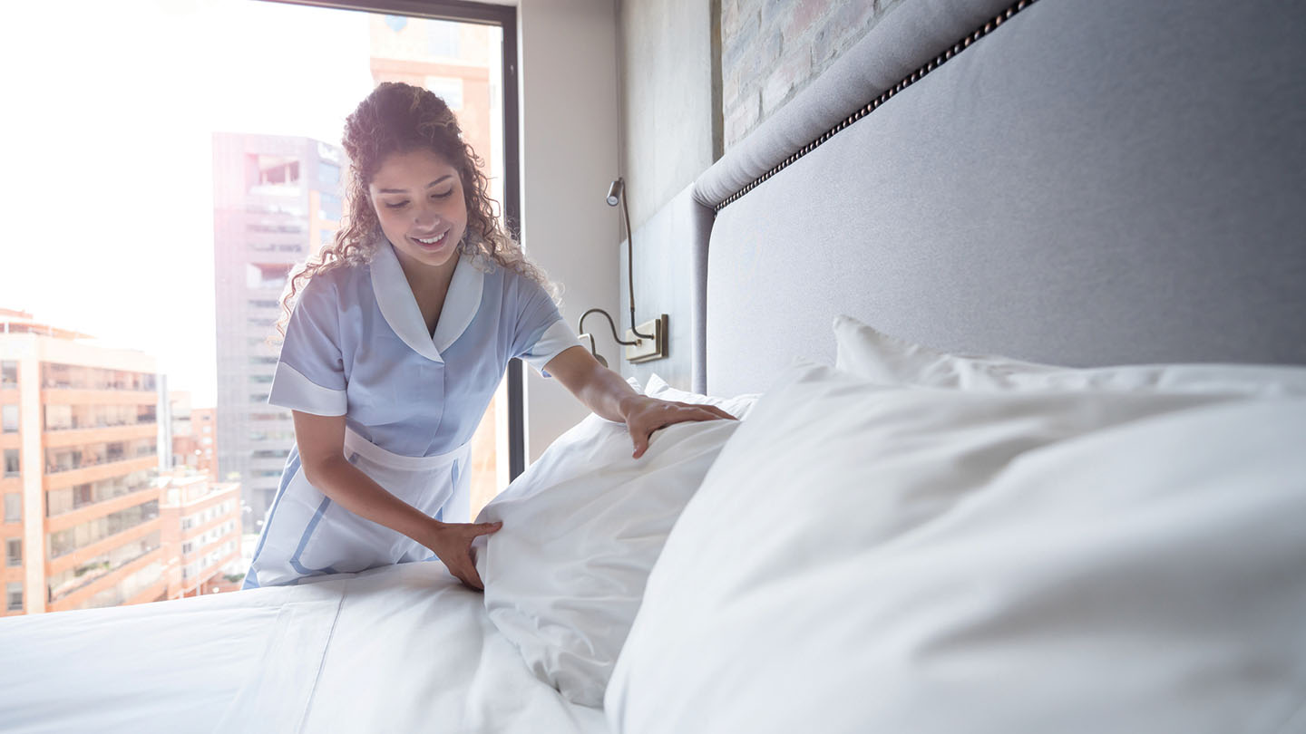 Hotel worker fluffing bed pillows