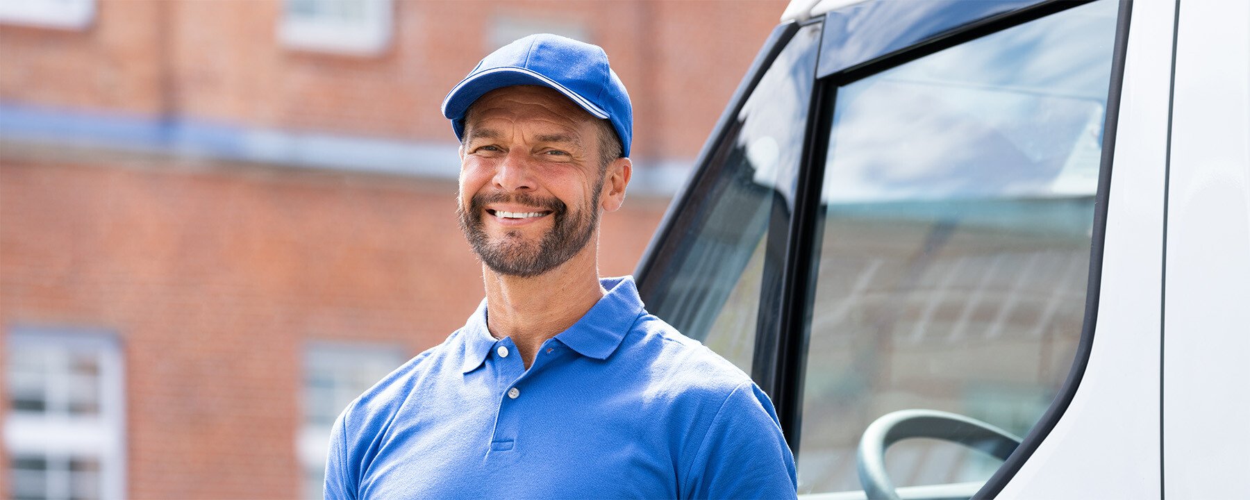 Man wearing blue cap and blue shirt standing outside of building