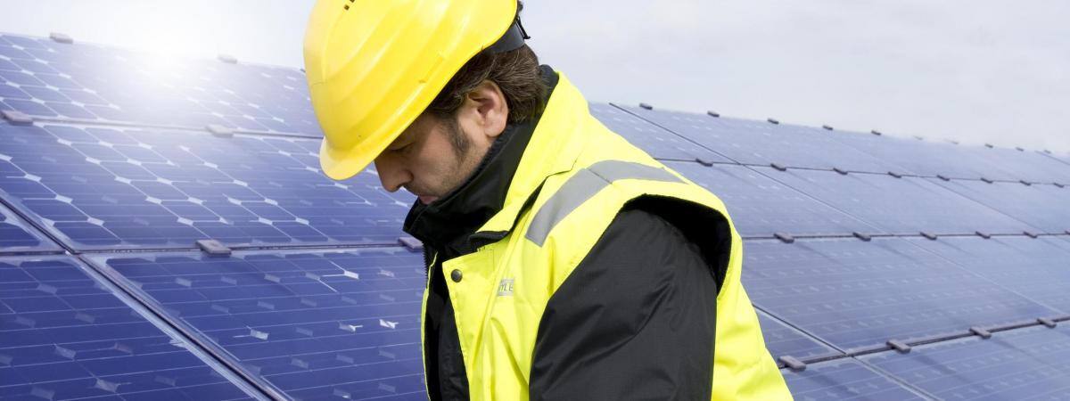 A worker in a hard hat installs solar panels