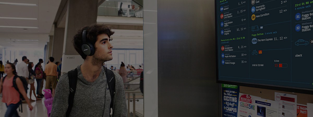A man looks at a transit screen in a busy station