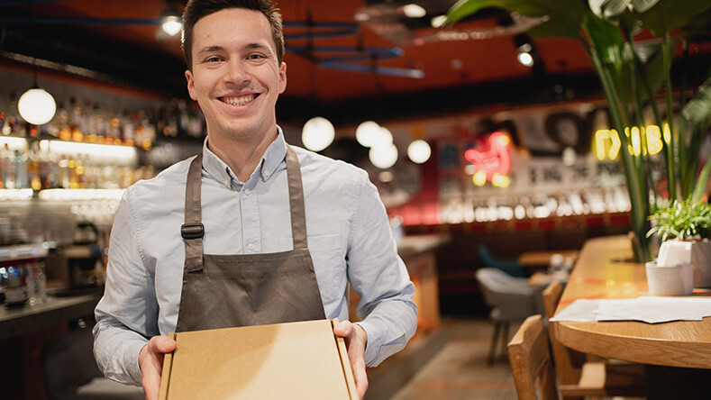 A server in a restaurant holds a takeout box
