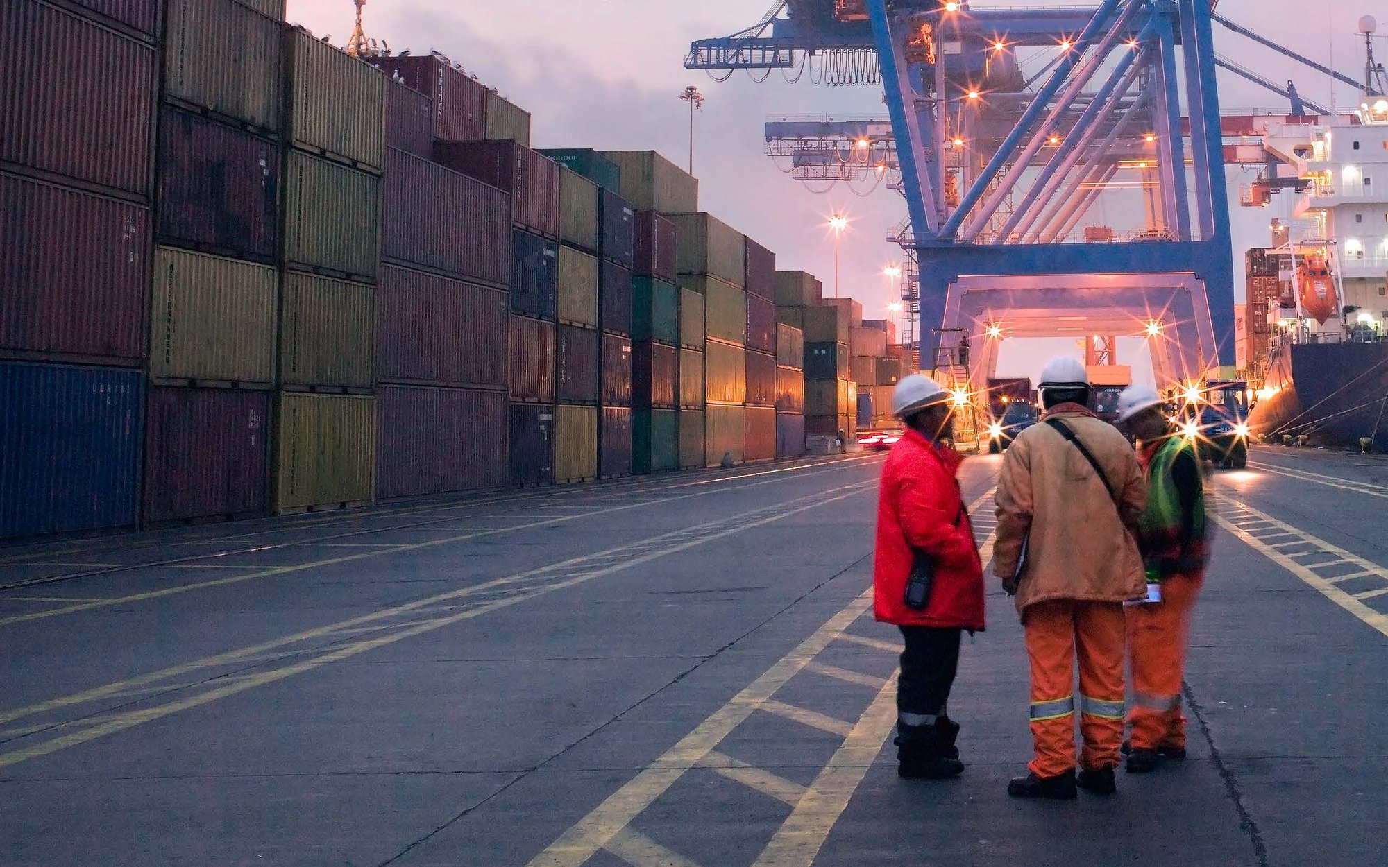 Workers stand in a shipping yard