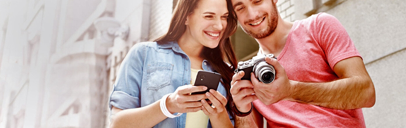 A man and woman look at the screen of a camera