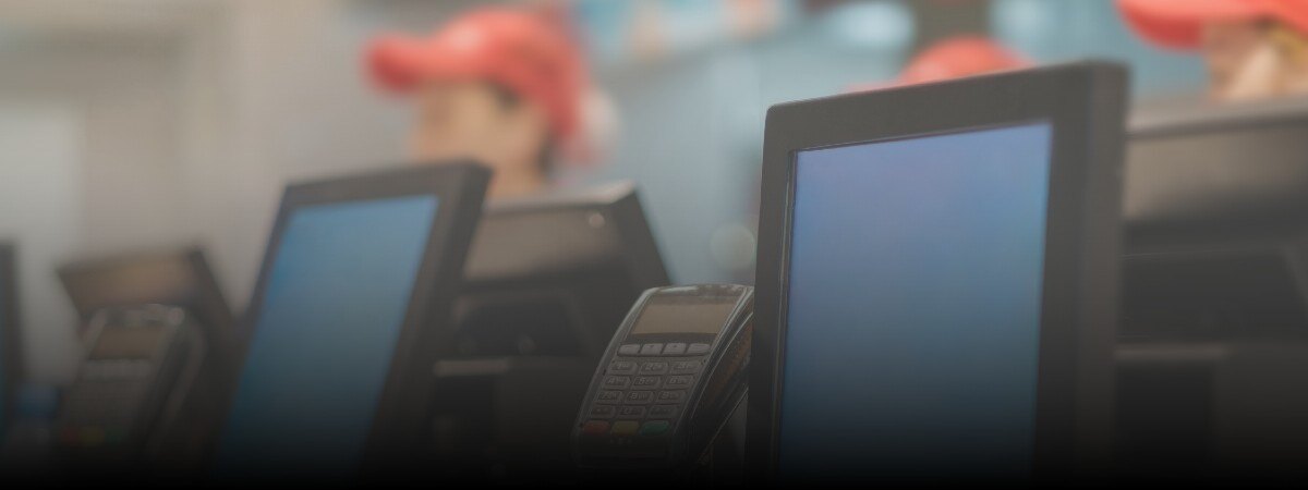 A row of computer monitors and card payment terminals