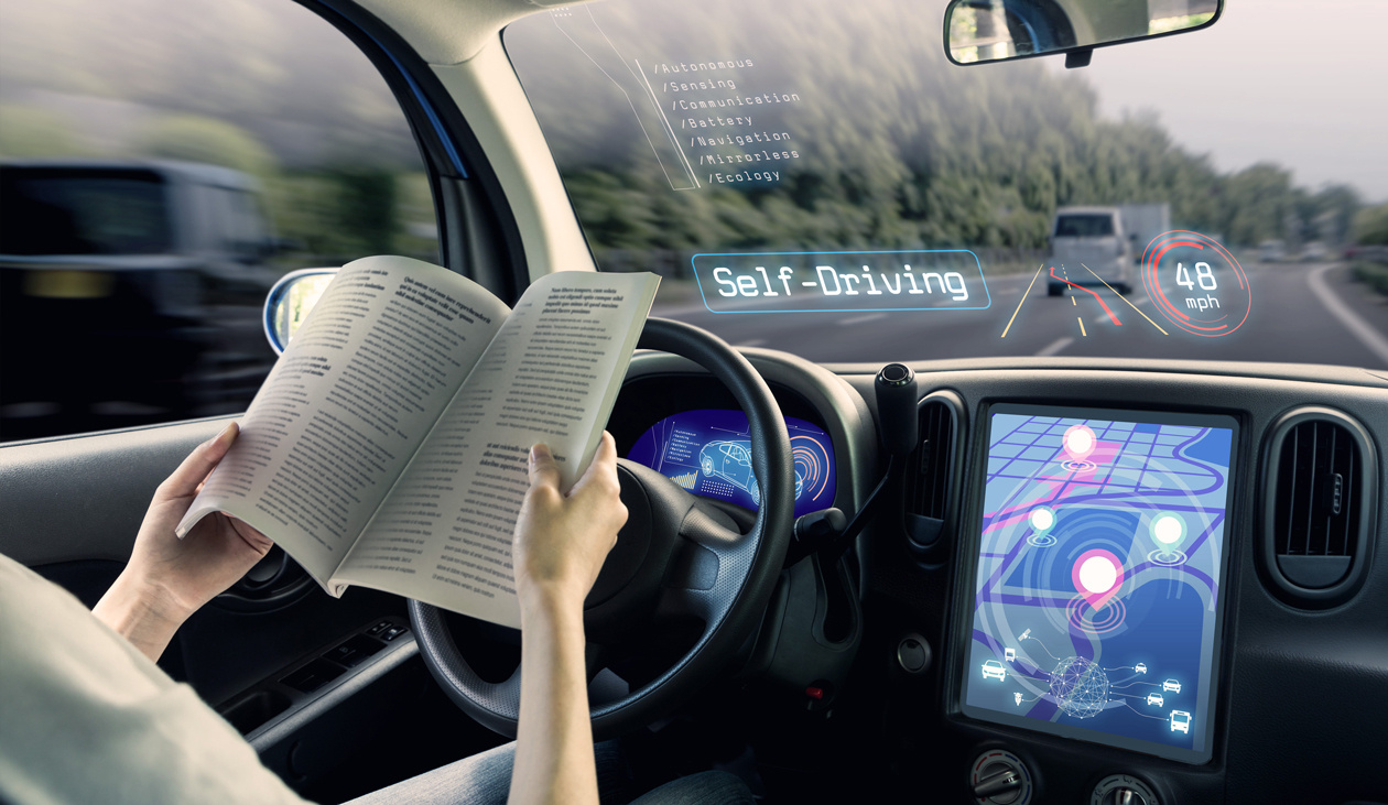 A driver reads a magazine behind the wheel of a self-driving car with a futuristic digital windshield overlay