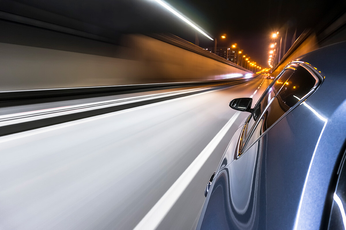 A car drives along a road at night