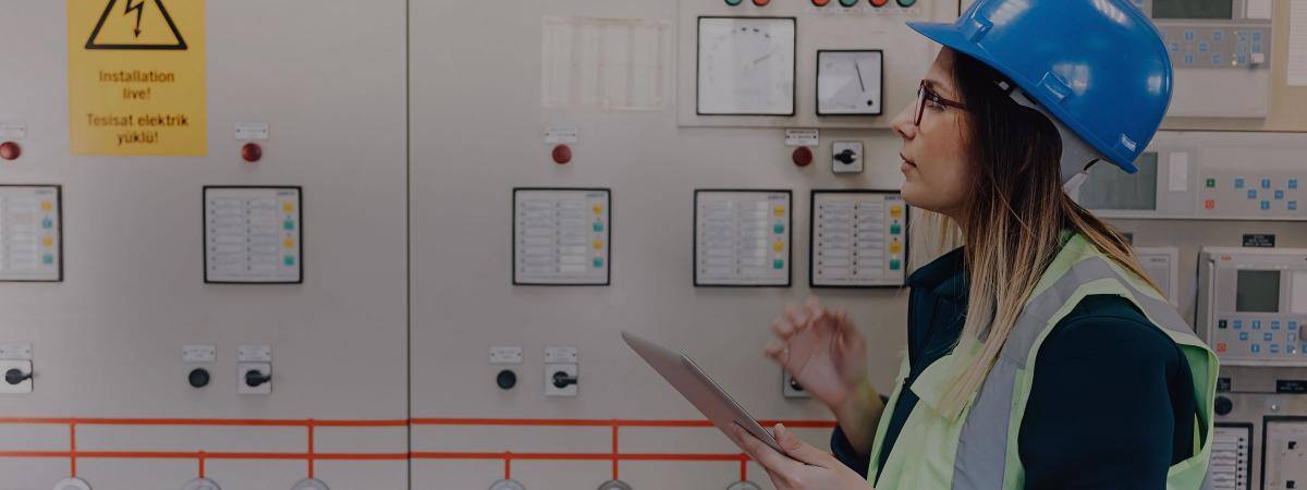 A working in a hardhat looks at readings on a machine