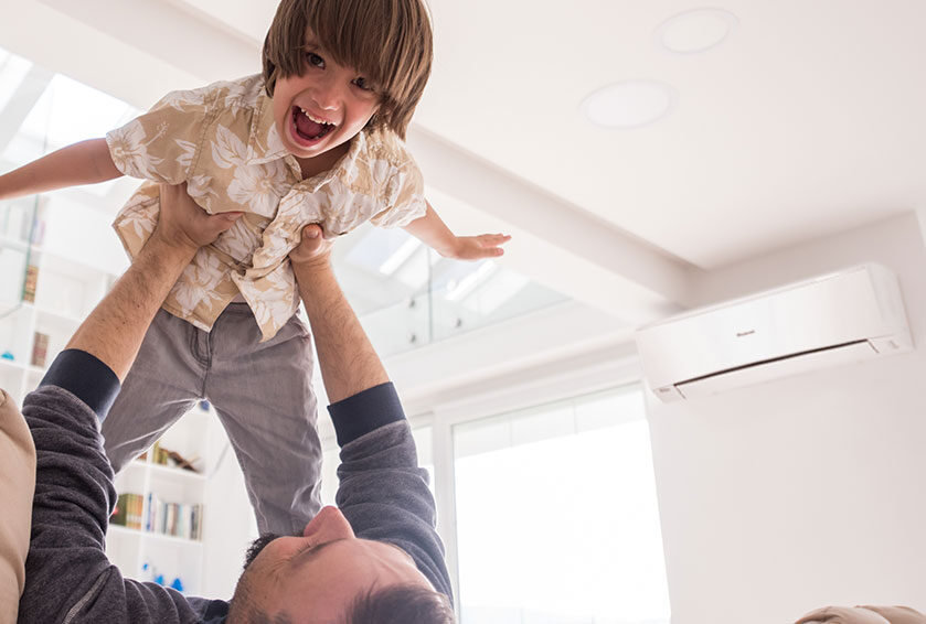 Father holder his son above his head while son happily holds arms and legs out