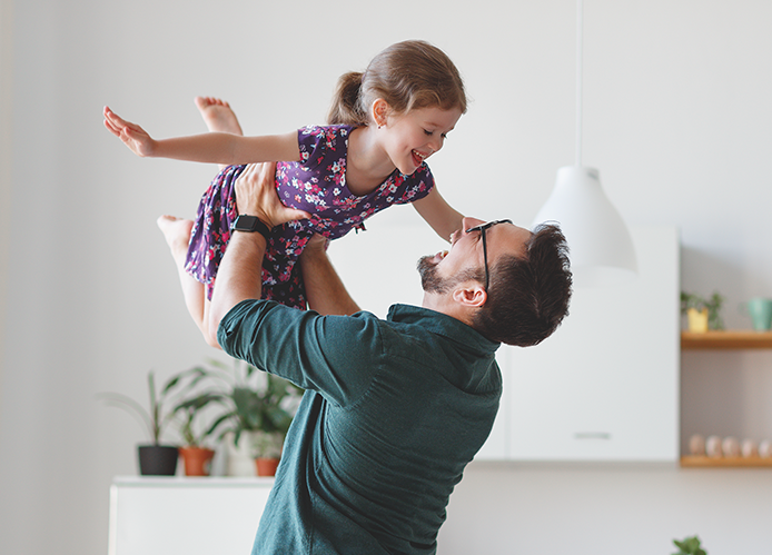 Man holding daughter in the air above his head