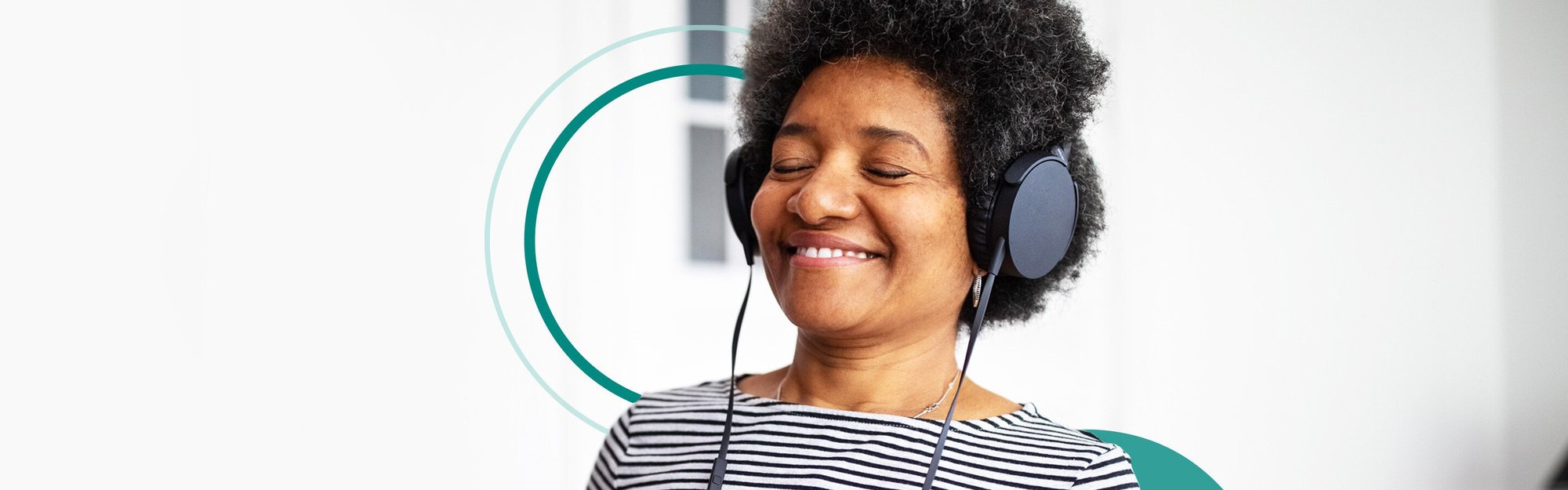 Woman with over the hear headphones on, listening to music and smiling while holding open CD case