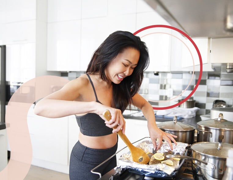 Woman in workout clothing cooking in the kitchen while smiling