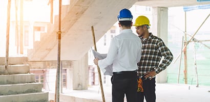 Contractor and engineer reviewing building plans in a condo construction site