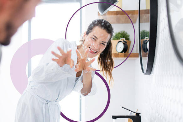 Femme souriant et atteignant un miroir de salle de bain.