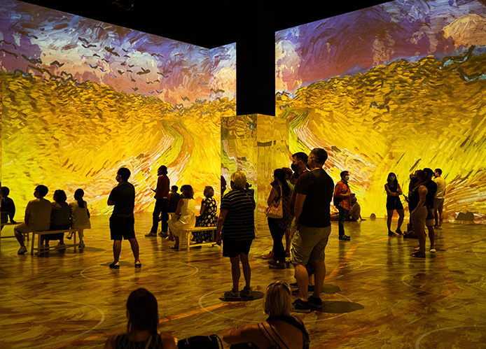 Des personnes regardant un mur de projection 3D immersive dans une galerie.