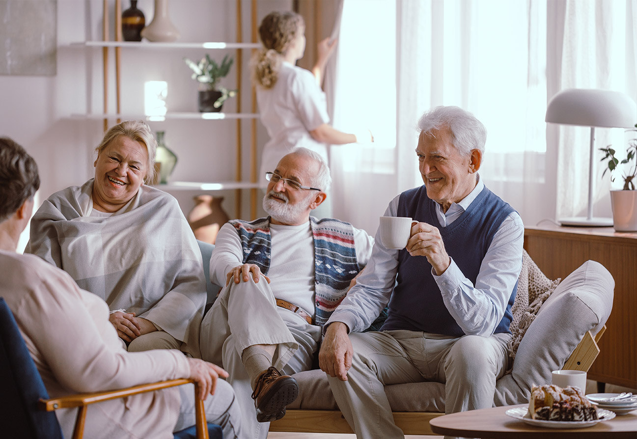 A group of seniors sit around a living room