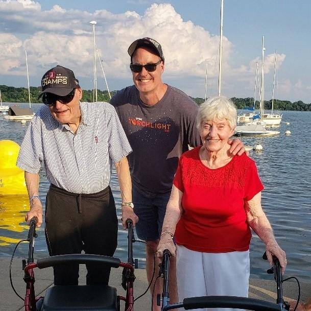 Bill Bachelor poses with two seniors on a dock