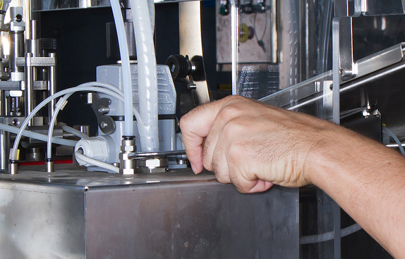 Hand adjusting a component on industrial machinery.