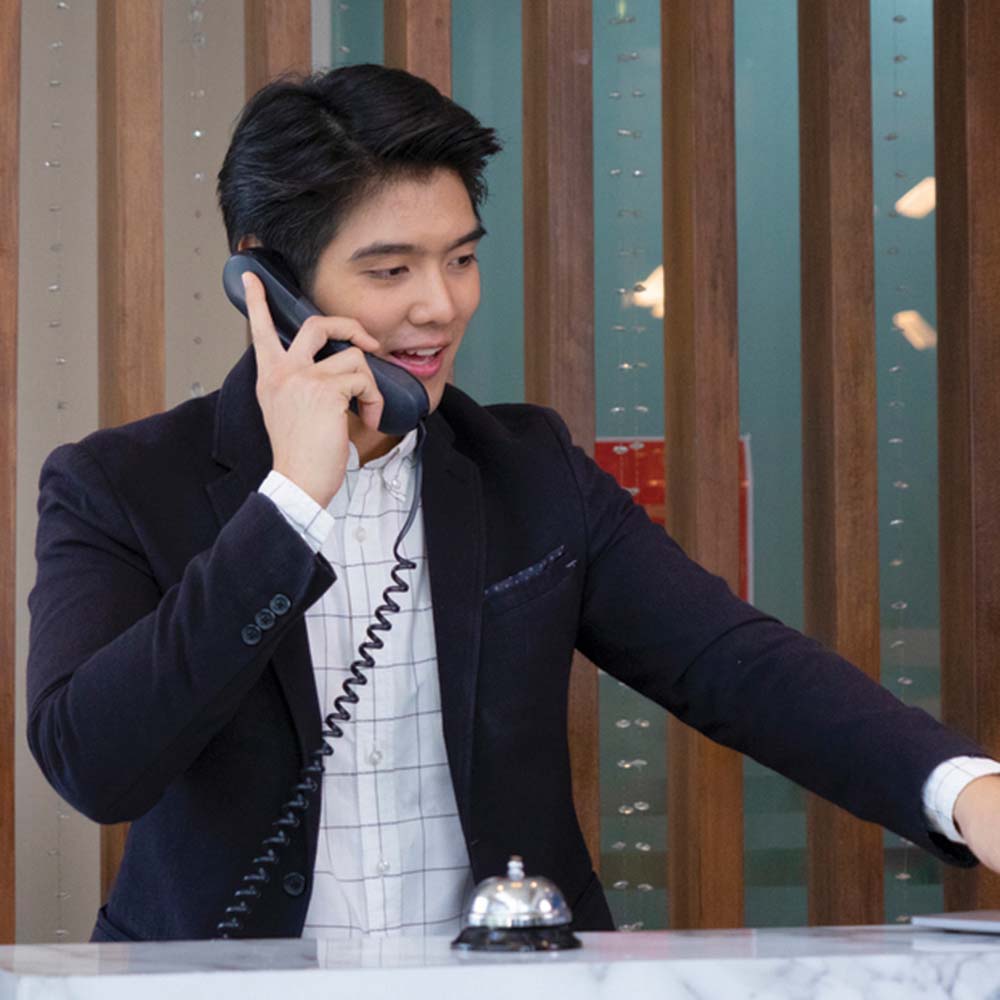 Man on phone at front desk of hotel