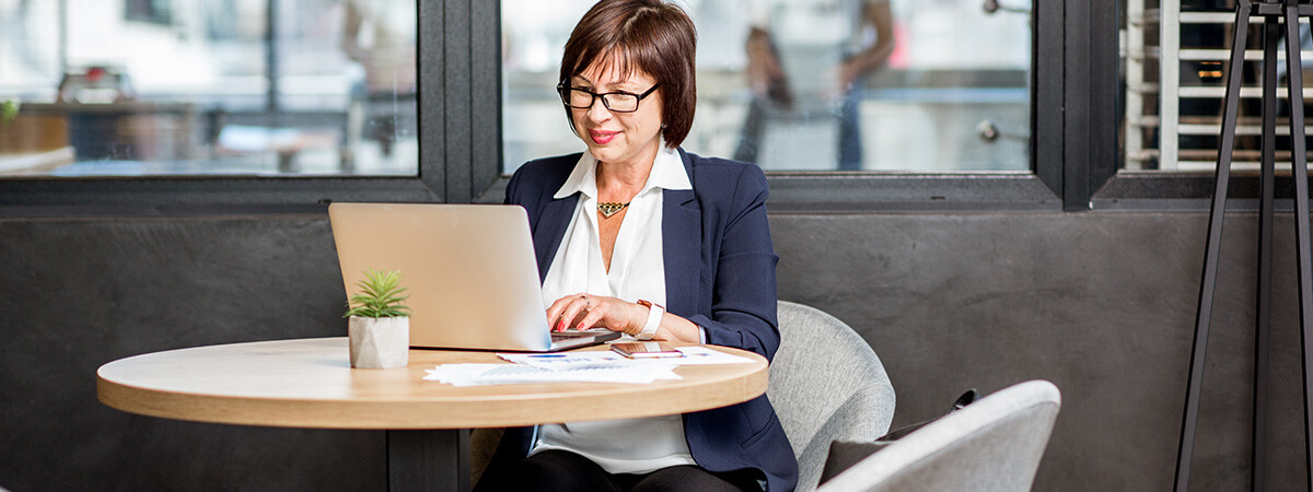 A woman sits at a table using a laptop