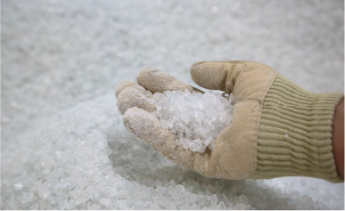 A gloved hand holds recycled plastic fragments