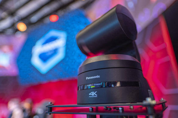 Panasonic 4K professional camera on stage with blurred logo background.