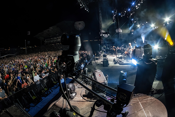 Stage view of a band performing to a large crowd at an outdoor concert.